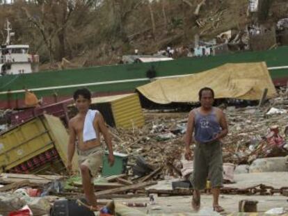Dos filipinos se abren paso entre los escombros de Tacloban.