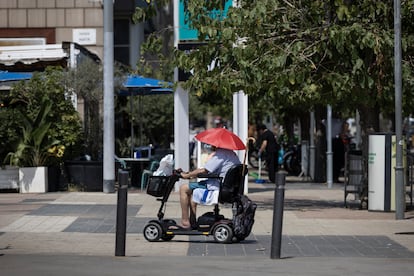 Un hombre circula por el paseo marítimo con una gorra parasol a la altura de la Torre Mapfre, en Barcelona, este lunes.