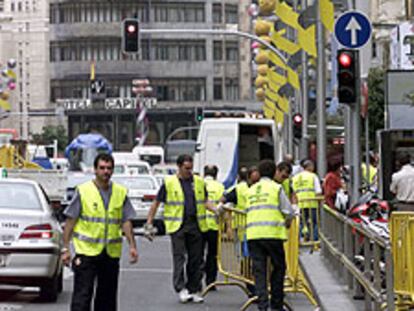 Varios operarios colocan vallas en la Gran Vía de Madrid.