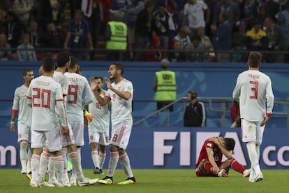 Saeid Ezatolahi se lamenta tumbado en el césped.mientras los jugadores de la selección española celebran su victoria.