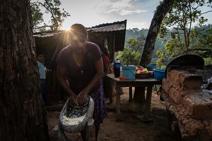 Laura Santiago, suegra de Justo, muele maíz junto a la cocina familiar.