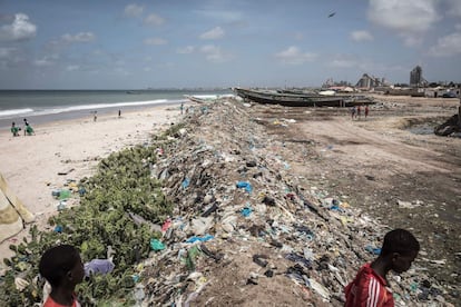 Jóvenes senegaleses caminan entre la basura amontonada a lo largo de la costa en Bargny el 15 de agosto de 2020. En 2014, el presidente de Senegal, Macky Sall, anunció el lanzamiento de un proyecto muy ambicioso para acelerar el desarrollo industrial del país. Fue bautizado Plan Senegal Emergente (PSE) y promete modernizar Senegal antes de 2035, algo que debería tener consecuencias para el suburbio de Bargny.