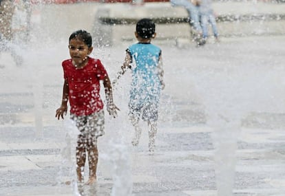 Una niña y un niño juegan con una fuente de agua en San José (Costa Rica).