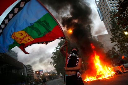 Un joven ondea una bandera de Chile junto a una barricada ardiendo, durante las protestas del viernes.