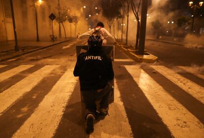 Un manifestante se esconde detrás de un escudo casero.