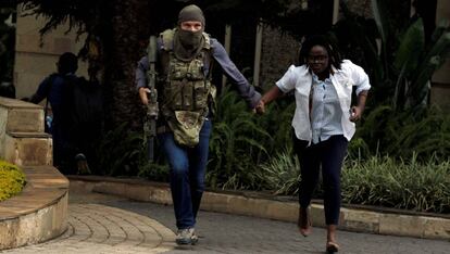 Un miembro de las fuerzas de seguridad kenianas evacúa a una mujer del hotel Dusit que fue atacado en Nairobi a mediados de enero.