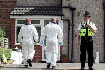 Dos policías con trajes especiales se disponen a entrar en una vivienda sospechosa ayer en Birmingham.