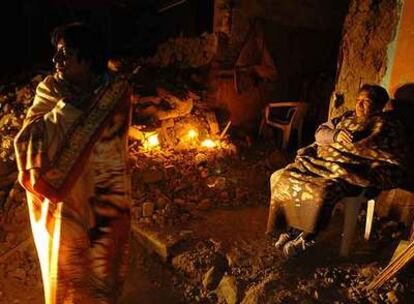 Miembros de una familia montan guardia a la puerta de su casa destruida por el terremoto en Cañete.