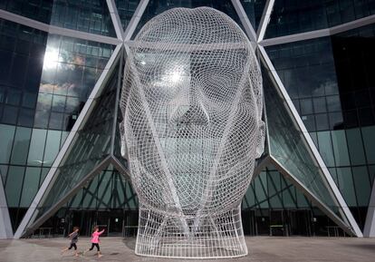 Dos niños corren cerca de la escultura titulada "Wonderland" del artista español Jaume Piensa en Calgary (Australia).