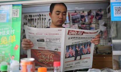 Un ciudadano chino lee un periódico que lleva a su portada una foto de la cumbre entre Trump y Kim.