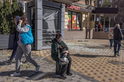 A woman sits on the street with her dog near one of the sites bombed on Monday in Kyiv.