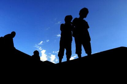 Un grupo de niños yemeníes caminan por un puente peatonal durante la puesta de sol en el casco antiguo de Saná (Yemen).