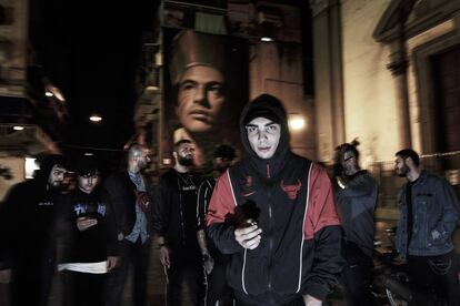 Um grupo de jovens do bairro de Forcella, reunido na noite napolitana em frente ao mural com a imagem de San Gennaro, obra do artista Jorit.