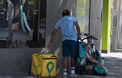 Un repartidor de Glovo camina con su bicicleta por la calle de Hortaleza.