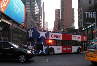 Un autobús turístico se cruza con los rayos del sol en la calle 42 de Nueva York.
