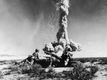 Tres soldados estadounidenses observan la explosión de una bomba atómica, en el desierto de Nevada en torno a 1950.