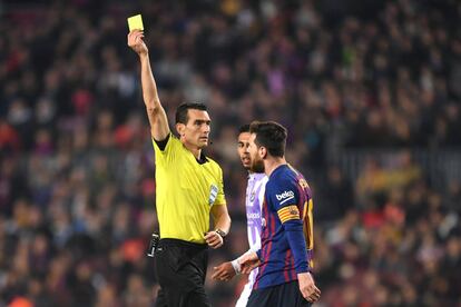 El árbitro Juan Martínez Munuera muestra una tarjeta amarilla a Lionel Messi.