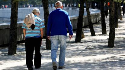 Dos personas de avanzada edad pasean por un parque de Madrid.