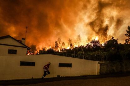 Un bombero se protege del incendio tras unas casas en Pampilhosa da Serra.