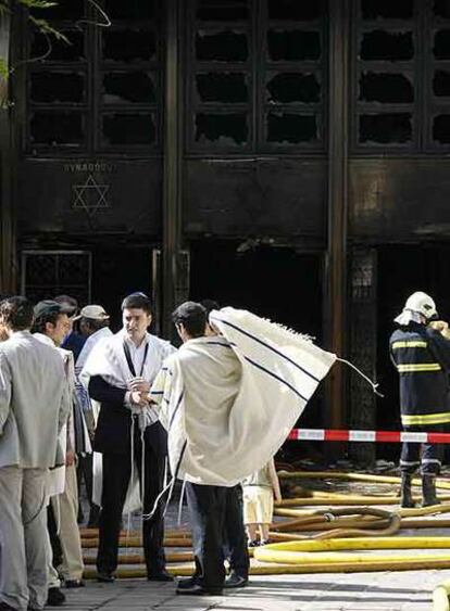 Varios judíos, ante la sinagoga destruida por el fuego en Ginebra.