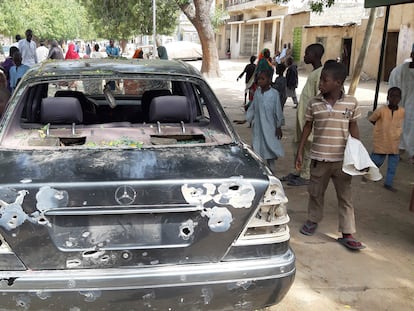 Ciudadanos junto a un coche dañado por el último ataque en la localidad nigeriana de Maiduguri, este miércoles.