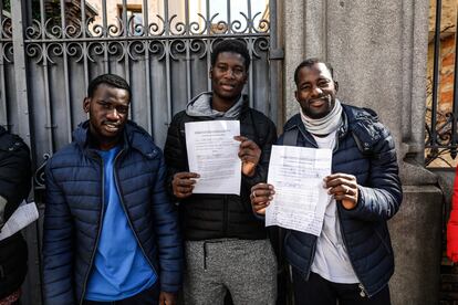 Tres migrantes, junto a los documentos presentados este martes ante el Defensor del Pueblo.