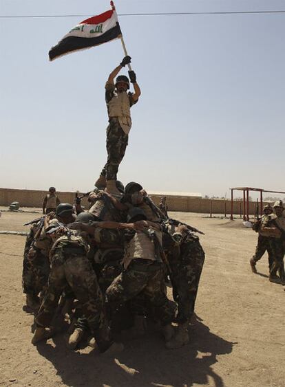 Soldados iraquíes sostienen una bandera de su país para los fotógrafos tras una sesión de entrenamiento en una base al sur de Bagdad.