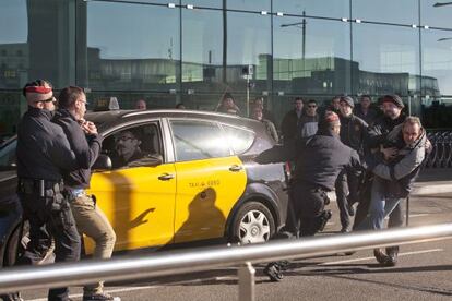 Agentes de los Mossos d&rsquo;Esquadra retienen a dos taxistas ante uno que acaba de llegar al aeropuerto de El Prat.