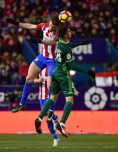 Saúl Ñíguez (i), del Atlético de Madrid, y José Carlos, del Betis, cabecean el balón.