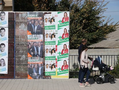 Una pareja con el carrito del bebé mira los carteles electorales de las andaluzas del 2-D en Las Gabias (Granada). 
 