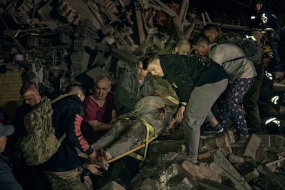 Personal de emergencias y voluntarios rescatan a una mujer embarazada entre los escombros de un edificio colapsado en Kiev, este jueves.