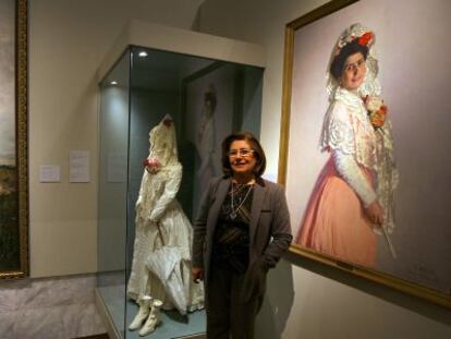 Victoria Liceras davant dos quadres i un vestit que formen part de l'exposició.