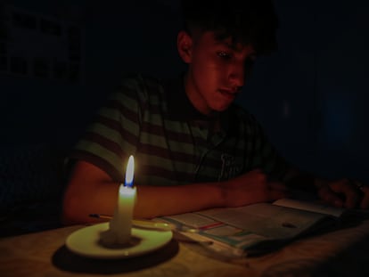 Un estudiante lee un texto a la luz de una vela en Quito, Ecuador, el 17 de abril de 2024.