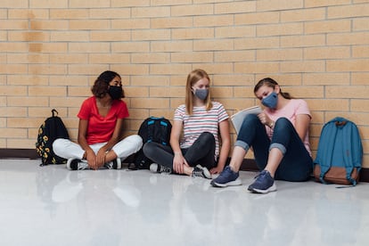 Tres alumnas se sientan en los pasillos de un instituto.