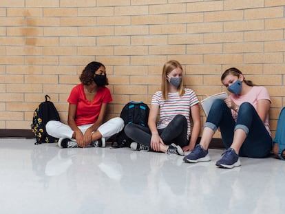 Tres alumnas se sientan en los pasillos de un instituto.