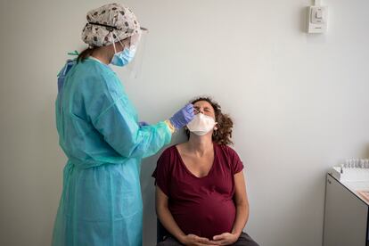 Una enfermera toma una muestra nasofaríngea a una mujer embarazada para realizarle una prueba de detección de la covid