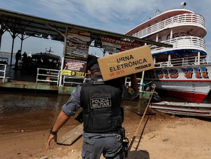 Un miembro de la Policía Militar ayuda al comité electoral a llevar las urnas electrónicas a las comunidades indígenas de Rio Negro, este sábado.