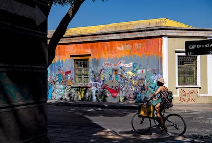 Una mujer pasea en bicicleta por el barrio de Yungay, un barrio tradicional y bohemio del centro de Santiago donde vivirá el presidente Gabriel Boric.