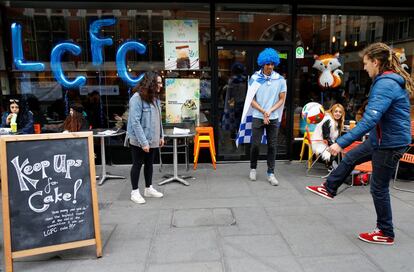 Aficionados del Leicester se entretienen esperando al partido contra el Manchester enfrente de una cafetería con los colores del Leicester.