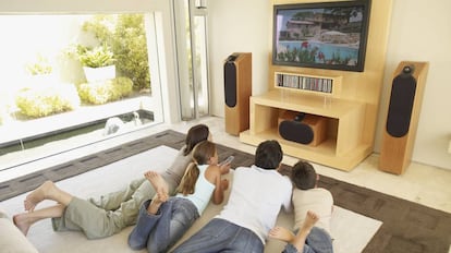 Una familia ve una película en el salón de casa.