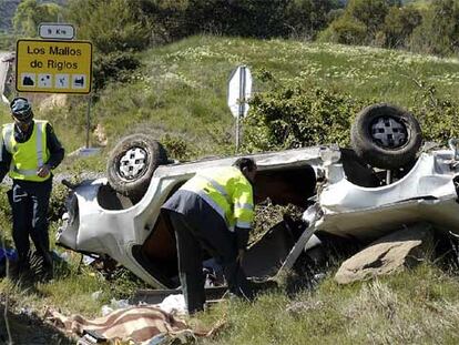 Guardias civiles examinan un coche que volcó ayer en Huesca, entre Ayerbe y el desvío de Riglos.