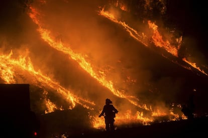 Al menos una persona ha muerto y más de 400 viviendas y negocios se han destruido hasta el momento en el rápido incendio forestal que se mantiene activo en el condado de Lake, en California, según han indicado altos cargos el domingo. En la imagen, un bombero junto a las llamas en Lower Lake, California.