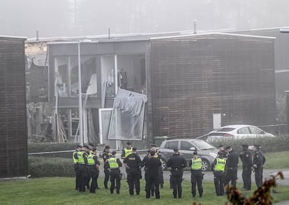Police officers stand in front of a building damaged after a powerful explosion in the residential area of Storvreta, outside Uppsala, Sweden, on September 28.