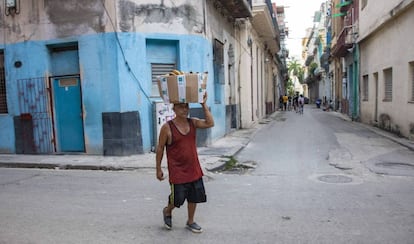 Un hombre camina con una cesta sobre la cabeza, en La Habana.