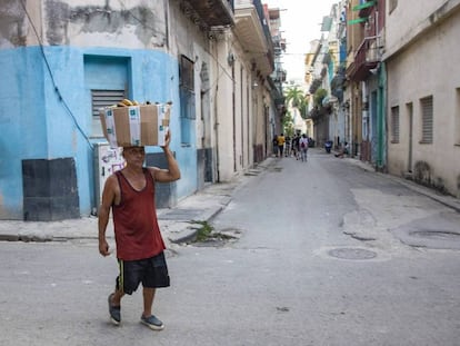Un hombre camina con una cesta sobre la cabeza, en La Habana.