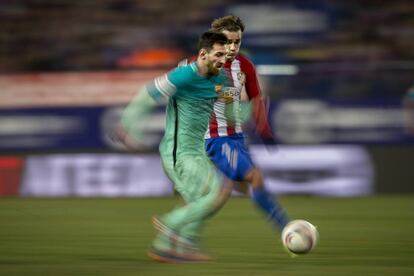 El jugador del Barcelona Leo Messi se lleva el bal&oacute;n ante Antoine Griezman