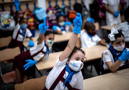 Con máscaras y guantes de plástico, para prevenir la propagación del coronavirus, niñas levantan la mano durante una clase en La Habana (Cuba), el 2 de noviembre de 2020. Decenas de miles de alumnos volvieron a la escuela por primera vez desde abril.