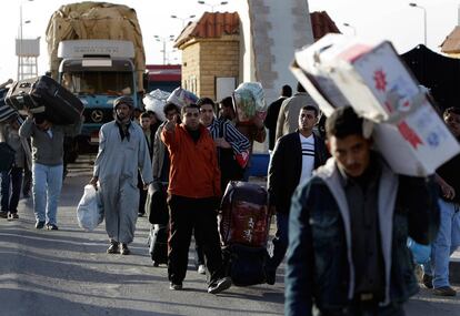 Un grupo de ciudadanos egipcios atraviesan el paso de Salloum, en la frontera entre Egipto y Libia. Se estima que unos 5.000 egipcios han abandonado el país y otros 10.000 esperan la salida.