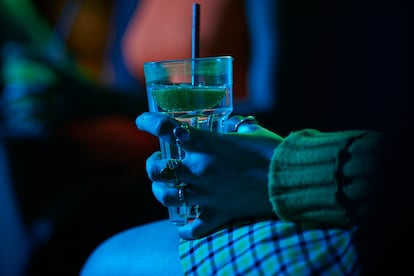 Una mujer sostiene una bebida en un bar.