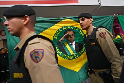 Integrantes de la Policía Militar de Minas Gerais caminan frente a una bandera brasileña con el rostro de Bolsonaro el 16 de agosto, día en que se inauguran las campañas presidenciales.